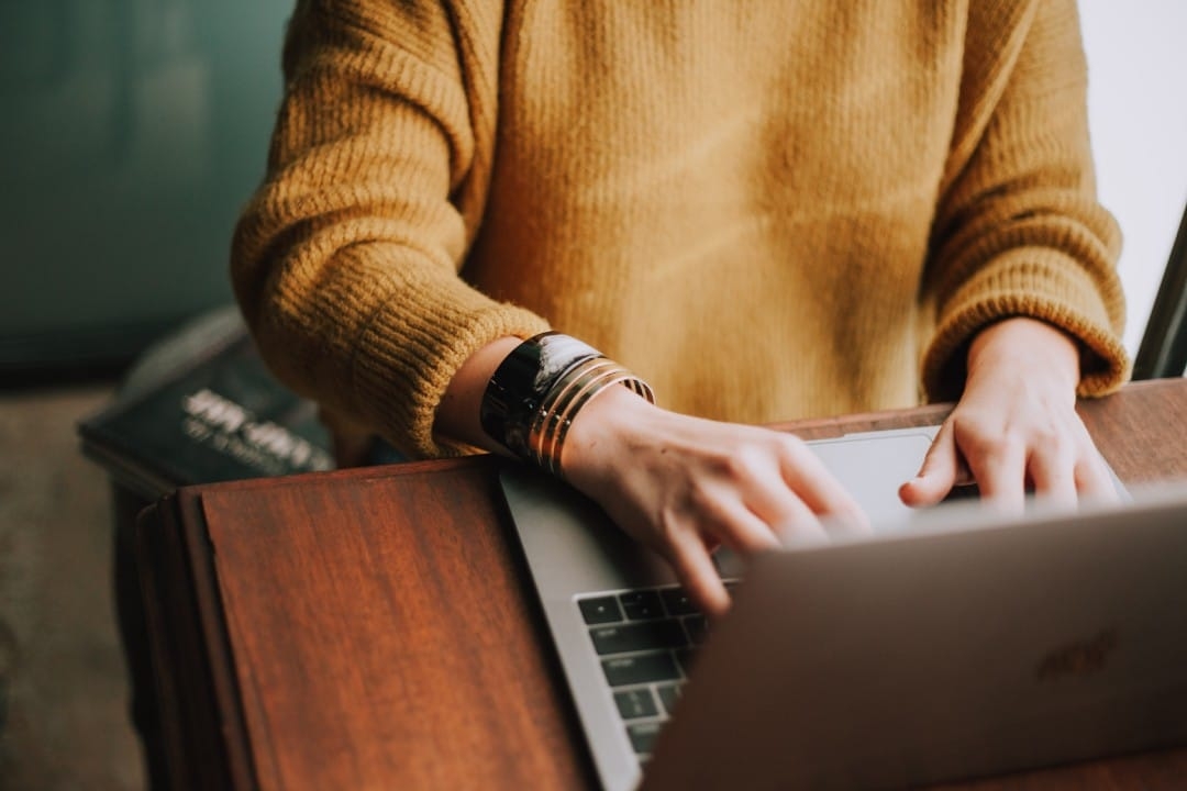 person-yellow-jumper-typing-at-desk-laptop.jpg