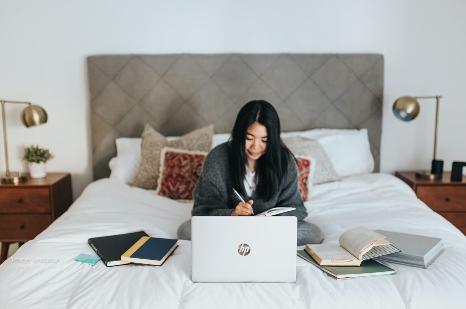 woman-sitting-on-bed-with-laptop-books.jpg