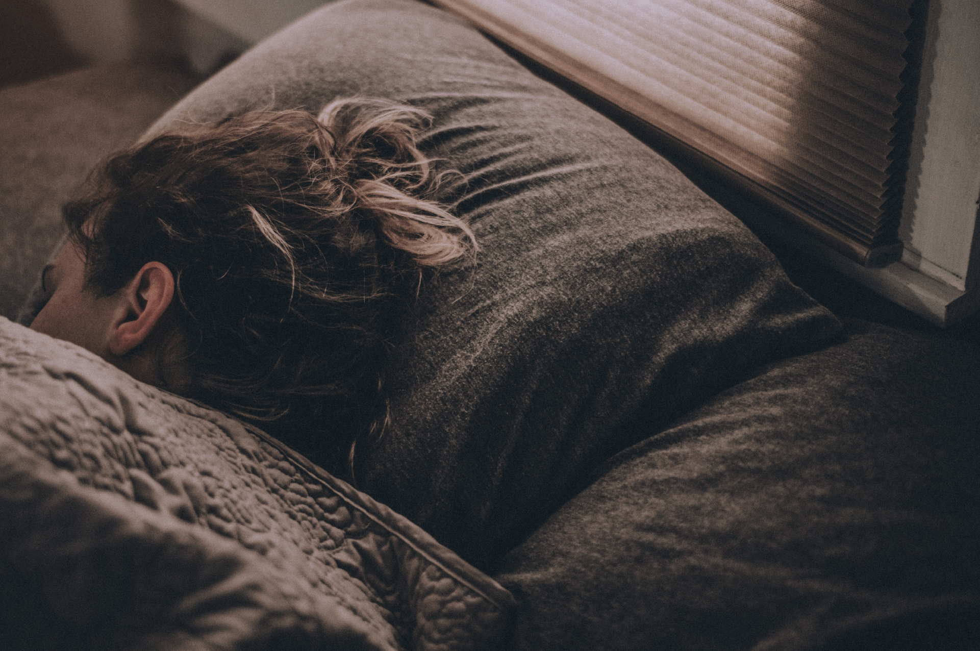 Woman sleeping on a grey bed