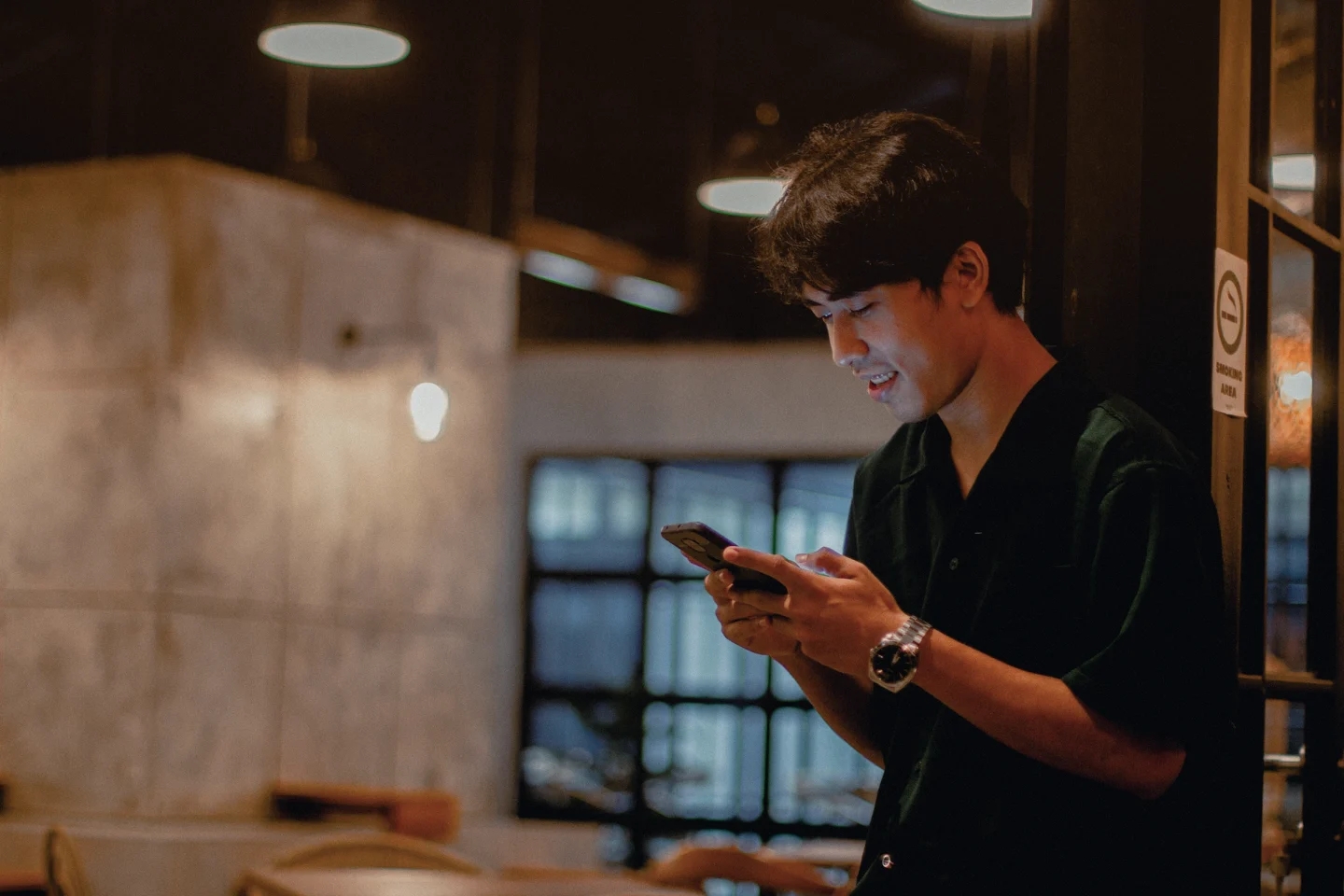 Male staring down at mobile in his hands